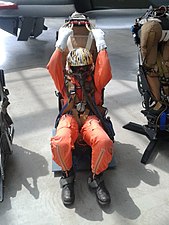 Illustration, avec un mannequin, de l'action d'un pilote voulant s'éjecter en tirant les poignées du haut de son siège.