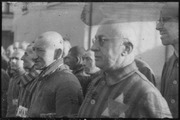 Sachsenhausen detainee with glasses in the foreground wears a two-color double-triangle ID-emblem.