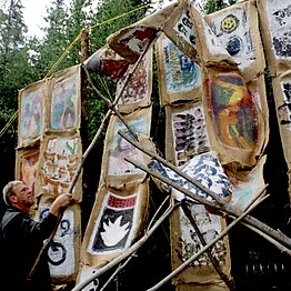 Les toiles de jute peintes par les participants sont attachées à des mâts par l'artiste Alain Laroche.