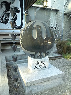 نصب حجري في معبد كومانو هونغو تايشا [الإنجليزية] يصور الغراب ثلاثي الأرجل الياباني ياتاغاراسو.