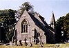 A flint church with steep roofs and an octagonal belfry and spire