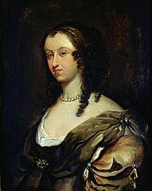 Portrait of woman with should length curly black hair and pearl necklace