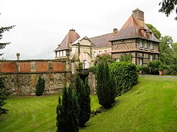 Blick auf das Wohngebäude mit der Mauer und dem Torbogen