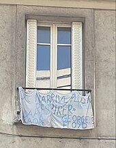 Photographie d'une banderole accrochée à la barrière d'une fenêtre, dans le 20e arrondissement de Paris. Il y est écrit "Je n'arrive plus à respirer. Adama Troaré. George Floyd.