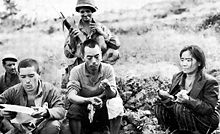 Two surrendered Japanese soldiers with a Japanese civilian and two US soldiers on Okinawa. The Japanese soldier on the left is reading a propaganda leaflet. Overcoming the last resistance.jpg