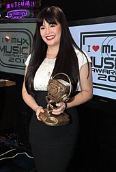 Velasquez holding a trophy for an award she has won
