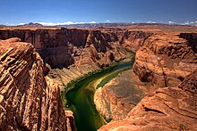 Вид на узкую зеленую реку, протекающую между высокими красновато-коричневыми скалами
