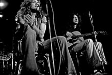 Černobílá fotografie Roberta Planta s tamburínou a Jimmyho Pagea s akustickou kytarou sedící a vystupující.