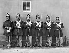черно-бяла снимка на шестима американски морски пехотинци, стоящи на опашка, пет с пушки от епохата на Гражданската война и един с подофицерски меч.