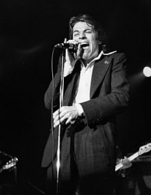 Palmer singing into a microphone onstage