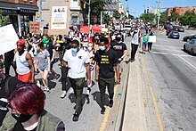 Протестующие в масках от COVID маршируют по улице Балтимора 30 мая