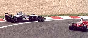 Photo de Schumacher sur Ferrari dépassant Räikkönen sur McLaren-Mercedes par l'intérieur du virage.