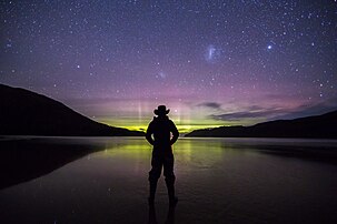 Un randonneur, dont la silhouette se découpe à contre-jour, contemplant une aurore polaire australe apparaissant à l'horizon de New Harbour Beach, dans le Southwest National Park en Tasmanie. (définition réelle 6 720 × 4 480)