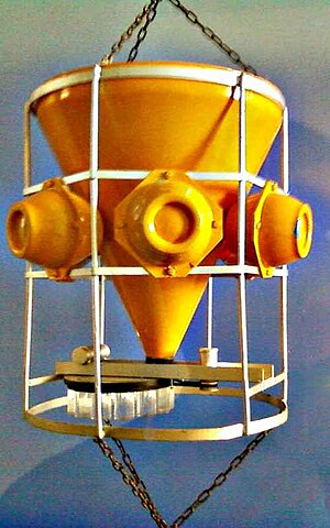 Model of a sediment trap: It mainly consists of a huge funnel, a ring of Glass floats (3 are visible) and a revolving wheel with sample bottles. BrnBldSedimentTrap.jpg