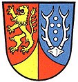 Landkreis Einbeck (1950–1974) Im geteilten Schild rechts in Rot ein aufrechter blaubewehrter und blaubezungter goldener Löwe, links in Blau ein silbernes Achtender-Hirschgeweih, zwischen den Stangen fünf silberne Kugeln in Kreuzform, unten eine von Gold und Rot steigende geschweifte Spitze. → Details