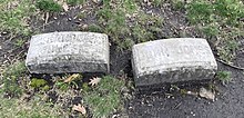 Two simple oblong gravestones on grass - the left reads "Grandma Jonesie" and the right reads "John Jones", both in sans-serif font