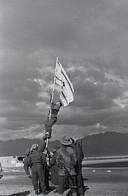 הנפת דגל הדיו באום-רשרש על ידי אברהם אדן ("ברן") בתום מבצע עובדה. צילום מאת מיכה פרי.