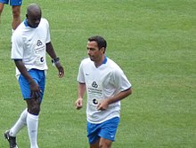 Deux footballeurs en maillot blanc et short bleu.