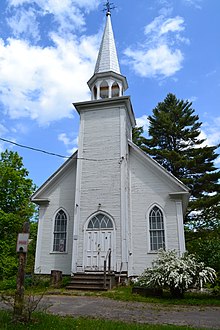 Une église modeste de couleur blanche avec un cocher à l'avant.