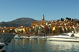 The harbour o Menton, wi the basilica o Saint-Michel-Archange beyond, viewed frae the Quai Napoléon III