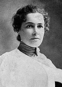 A young white woman wearing a high-collared dress or blouse; her dark hair is dressed back, with some curls around her temples.