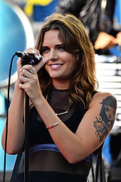 Swedish singer Tove Lo smiling as she holds a microphone on-stage