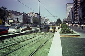 Un tram 18 en direction de Fort Jaco sort du prémétro sur l'avenue de la Toison d'or et arrive à la place Louise. Il croise un tram 32 barré en direction de Jette avec en arrière-plan la porte de Namur (1985)