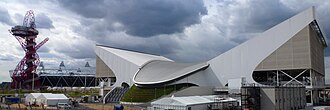 Vue extérieure du London Aquatics Centre avec le stade olympique en arrière plan.