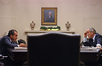 Никсон сидит за большим столом с президентом Джонсоном в Белом доме.