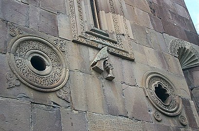 Détail de la façade sud : les deux oculi, la fenêtre centrale, une colombe sur un perchoir et la partie supérieure d'une des niches[1].