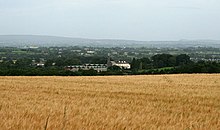 Photographie d'un bâtiment religieux moderne depuis un champ situé sur une colline