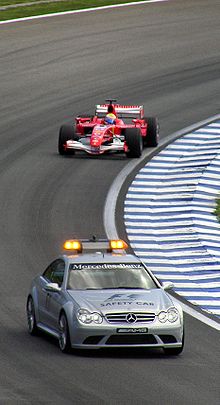 Photo d'une voiture grise et d'une monoplace de Formule 1 rouge en piste