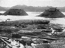 Photo en noir et blanc de débris de maisons au milieu de l'eau