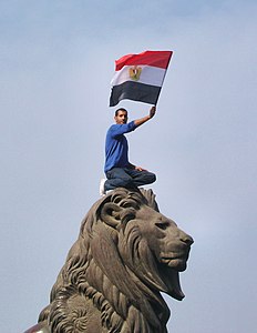 أحد المتظاهرين يقف على تمثال أحد أسود كوبري قصر النيل بجانب ميدان التحرير. خلال ثورة 25 يناير
