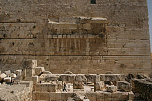 slightly curved blocks form the spring of an arch in the middle of a wall of otherwise flat-faced stones