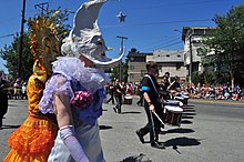 L’édition 2015 du Fremont Solstice parade, photographie laissant apparaître en premier plan deux humains qui revêtent un masque en forme de lune et soleil mixés à un visage