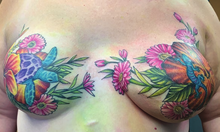 A woman's breasts after a mastectomy, tattooed over with bright-colored flowers