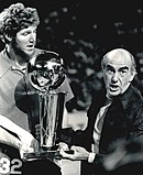 Bill Walton (maldekstre) kaj Jack Ramsay (dekstra) tenanta la 1977-datita NBA-Ĉampioneco-trofeon.