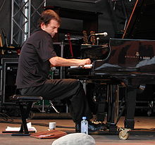 Photographie d'un homme assis et jouant du piano.