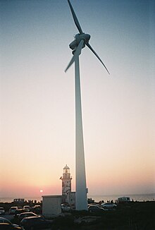 Small wind turbine with lighthouse in the background