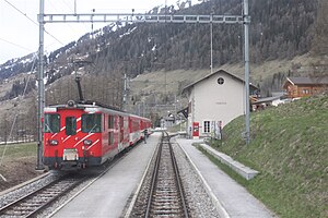 Red-and-white train at two-story station building