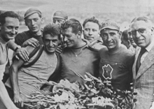 Photographie en noir et blanc montrant des coureurs félicités à l'arrivée du Tour.