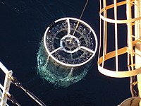 A CTD-rosette comes up out of the water just before it gets recovered and brought on deck of the ship.