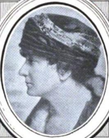 A white woman photographed in profile, wearing a substantial hat