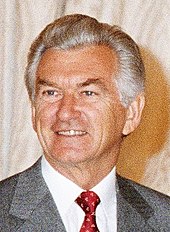 Der australische Premierminister Hawke vor einem hellen Hintergrund. Das Bild zeigt seinen Kopf und die Schultern, er trägt einen grauen Anzug, weißes Hamd und rote Krawatte. Er ist leicht nach rechts gedreht, sein graues Haar färbt sich an den Ansätzen weiß.