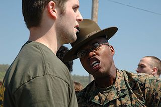 Sergeant Paul Nixon, drill instructor, 3rd Recruit Training Battalion, Marine Corps Recruit Depot Parris Island, South Carolina, gives a poolee some added incentive to do what he’s told. Approximately 400 future Marines gathered May 7, 2005 at Fort Indian Town Gap, Pennsylvania, for Recruiting Station Harrisburg’s Annual Future Marine Challenge. The purpose of the event is to familiarize the future Marines with boot camp and to allow them to learn about teamwork and camaraderie. (original caption) Date07.05.2005 Sourcewww.usmc.mil images AuthorStaff Sergeant J.L. Wright Jr. via Wikimedia Commons