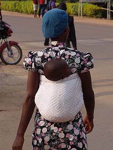 Egy asszony a hátára kötött gyermekével