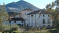 En primer plano, un cortijo, al fondo, ladera cubierta de olivares y el núcleo de población de Solera (Jaén).