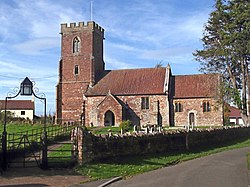 Reddish stone building with square tower.