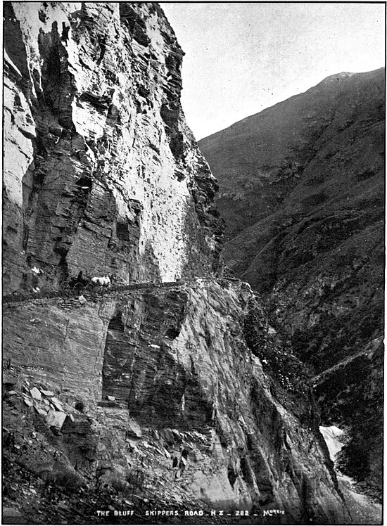 Skipper's Canyon Road, Queenstown - a road cut into a cliff face with a large drop, horse and carriage, and rocky hills.